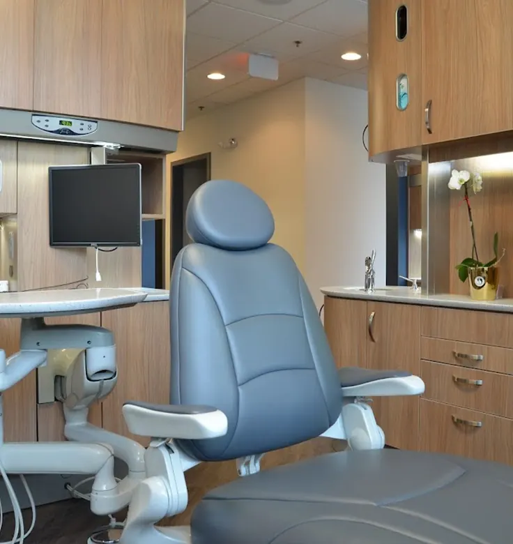 A treatment room at Severn River Dental Health Center, with a grey dental chair and wood cabinetry.
